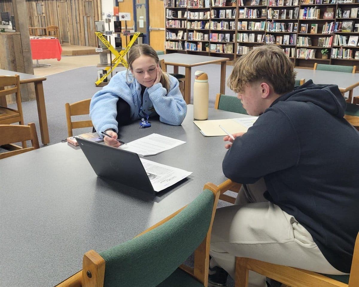 A PartnerCorps member helping a student with schoolwork in the school library